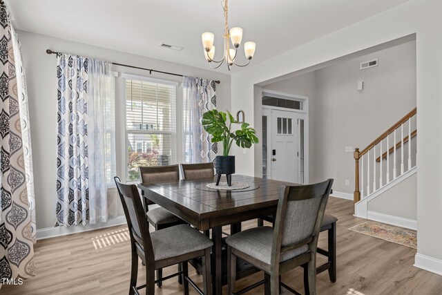 dining space featuring a chandelier, light wood-type flooring, stairway, and baseboards