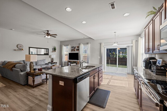 kitchen featuring stainless steel appliances, a sink, dark stone countertops, light wood-type flooring, and recessed lighting