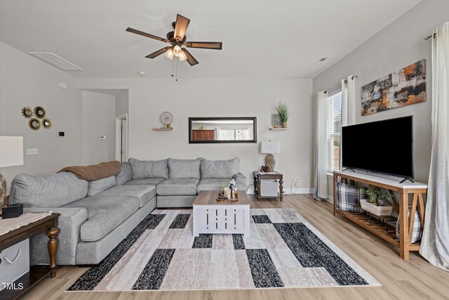 living area featuring wood finished floors, a ceiling fan, attic access, and baseboards
