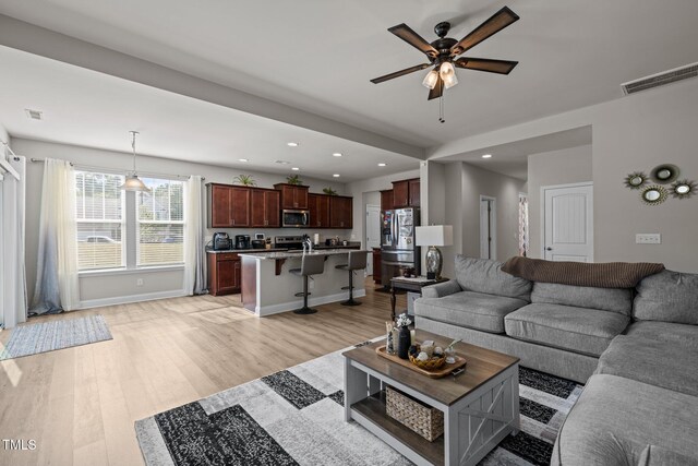living room with a ceiling fan, recessed lighting, light wood finished floors, and baseboards