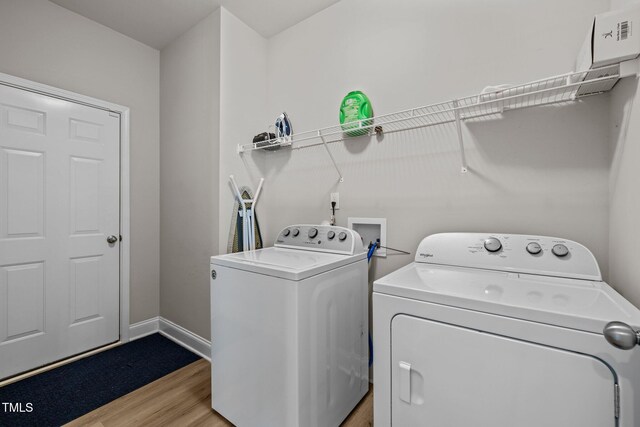 clothes washing area with washing machine and dryer, light wood-style floors, and baseboards