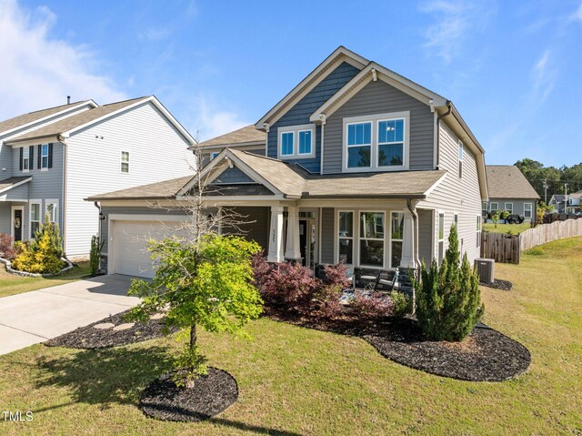 craftsman inspired home featuring driveway, cooling unit, covered porch, a garage, and a shingled roof
