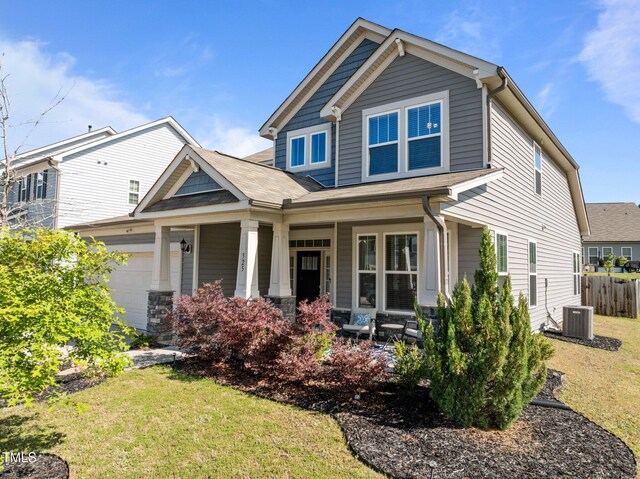 craftsman-style house featuring covered porch, central air condition unit, and a garage