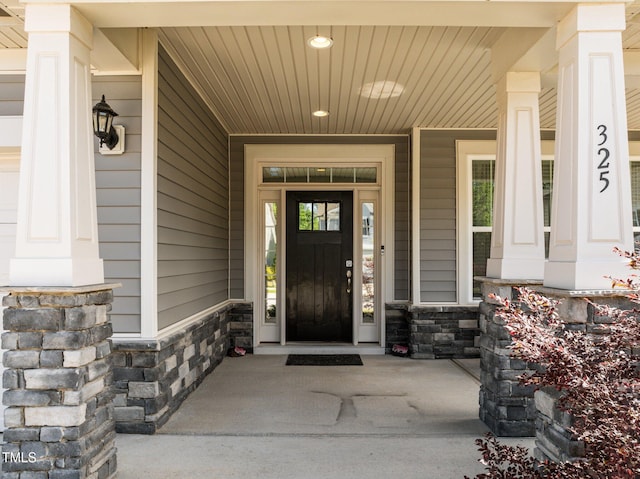 doorway to property featuring stone siding and a porch