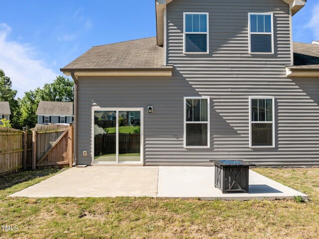 rear view of property featuring a patio, a gate, and a shingled roof