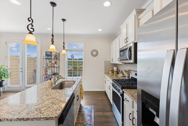 kitchen with stainless steel appliances, a sink, backsplash, an island with sink, and white cabinetry