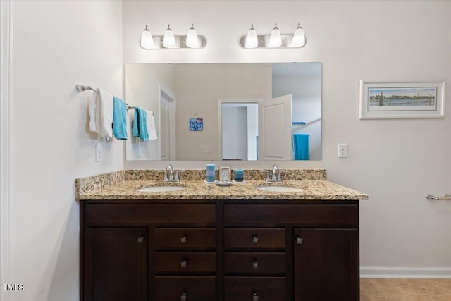full bath featuring double vanity and baseboards