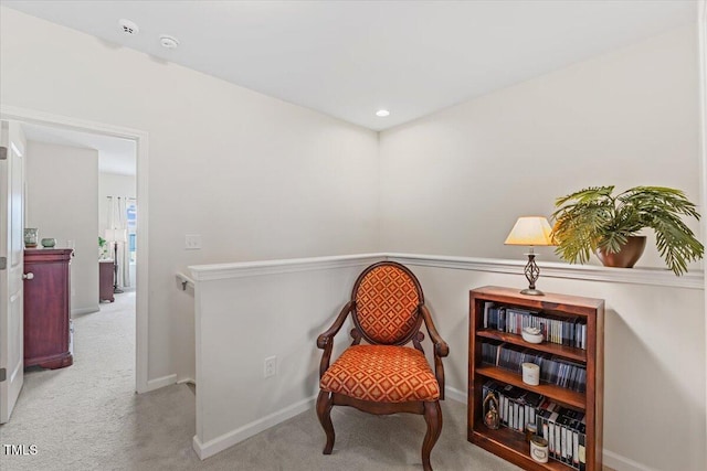 sitting room with carpet, baseboards, and an upstairs landing