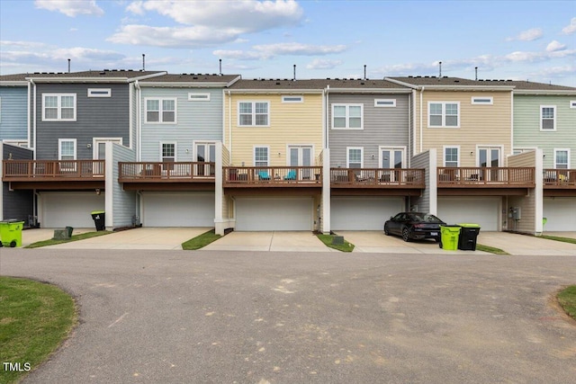 back of property with a garage, driveway, a wooden deck, and a residential view