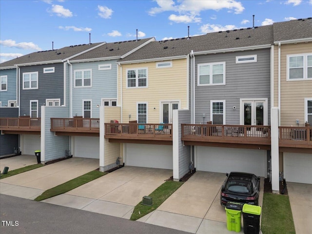rear view of house with an attached garage, concrete driveway, and a residential view