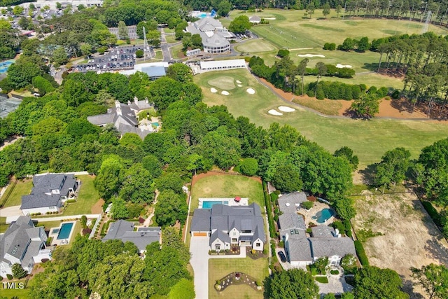 aerial overview of property's location with a golf club, nearby suburban area, and a tree filled landscape