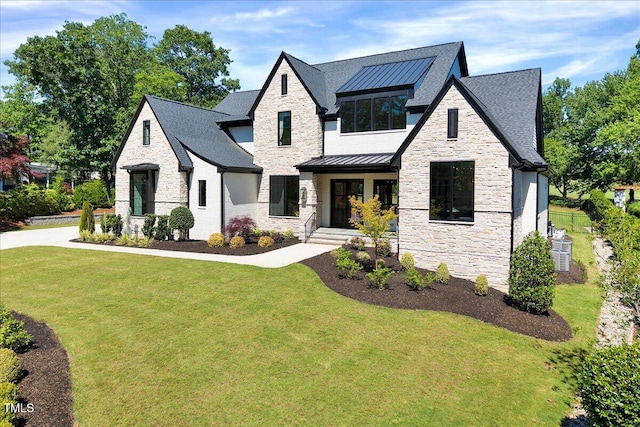 view of front of house featuring stone siding, a front lawn, a standing seam roof, and a shingled roof