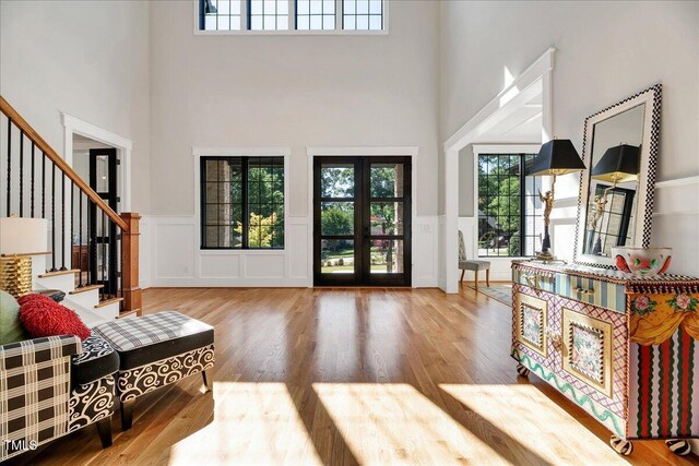 entrance foyer featuring a high ceiling, wood finished floors, stairs, wainscoting, and a decorative wall