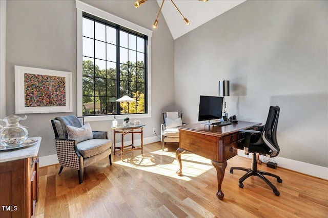 office area featuring light wood finished floors, baseboards, and high vaulted ceiling