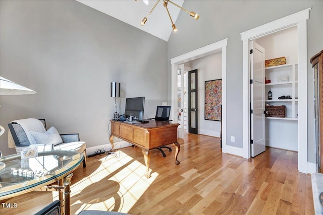 office area with high vaulted ceiling, a chandelier, light wood-type flooring, and baseboards