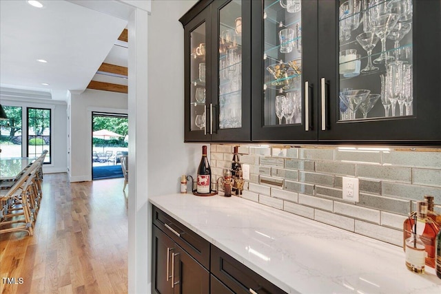 bar featuring light wood-style flooring, backsplash, recessed lighting, and baseboards