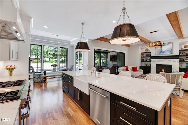 kitchen with stainless steel appliances, a sink, custom range hood, light wood-type flooring, and recessed lighting