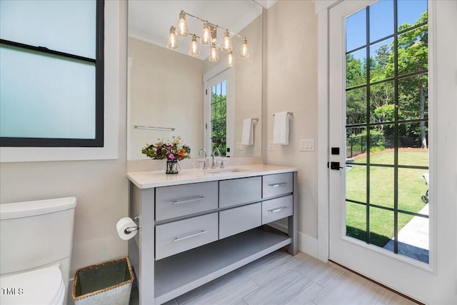 bathroom with toilet, vanity, and baseboards