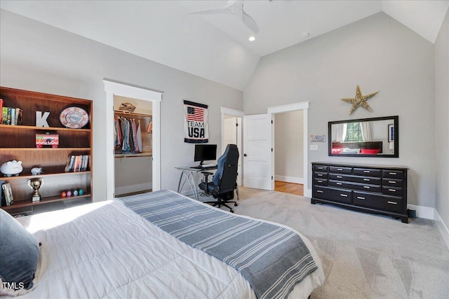 bedroom with high vaulted ceiling, baseboards, light colored carpet, a walk in closet, and a closet