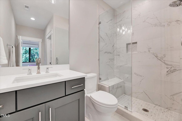 bathroom featuring a tile shower, toilet, and vanity