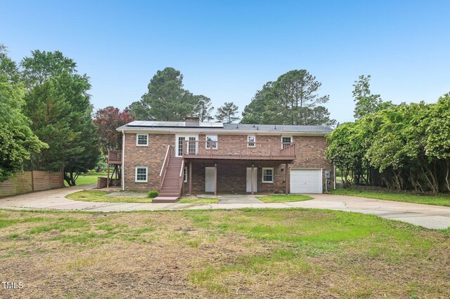 view of front of property with brick siding, concrete driveway, a front yard, stairway, and a wooden deck