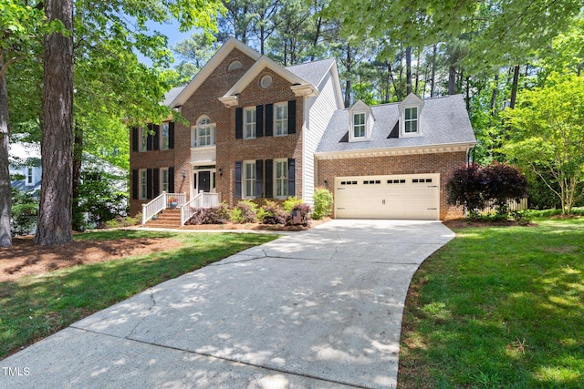 view of front of home featuring brick siding, driveway, a front yard, and a garage