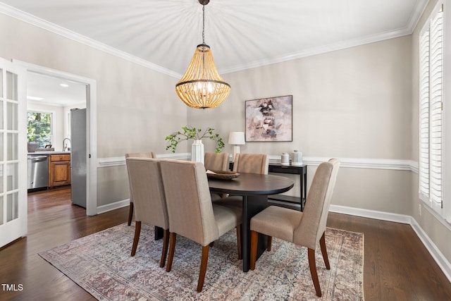 dining room featuring a chandelier, dark wood finished floors, ornamental molding, and baseboards