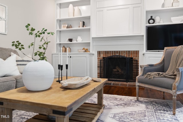 living area featuring wood finished floors, a fireplace, and built in features