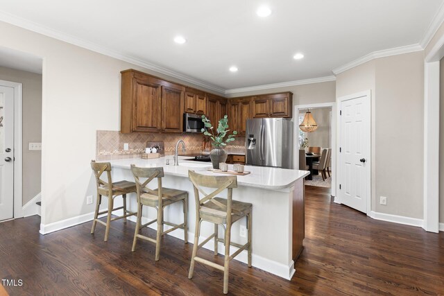 kitchen with appliances with stainless steel finishes, a peninsula, light countertops, tasteful backsplash, and dark wood-style flooring