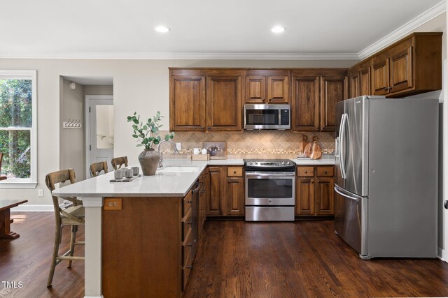 kitchen featuring appliances with stainless steel finishes, a peninsula, a sink, a breakfast bar, and light countertops