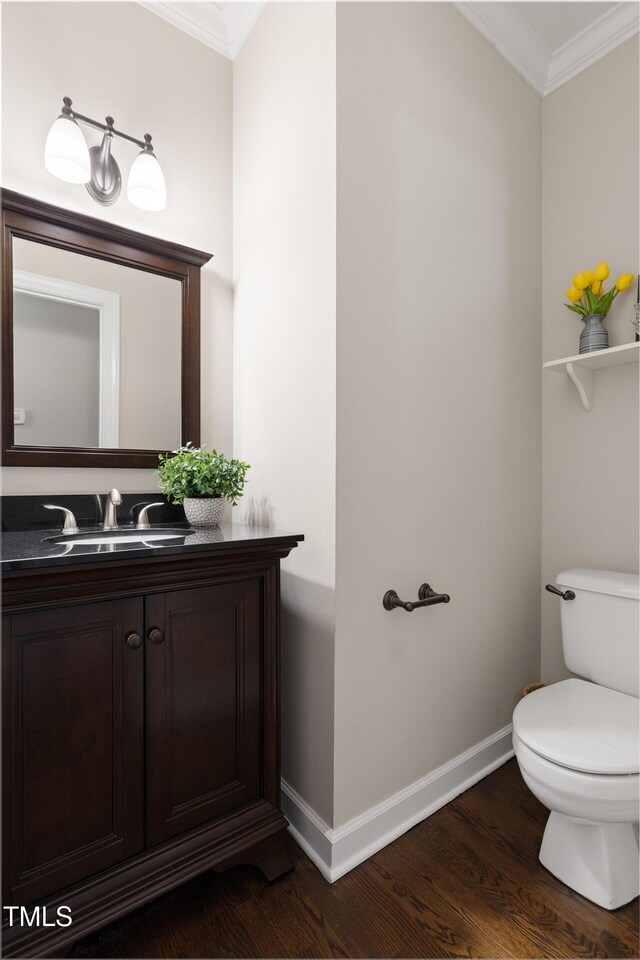 bathroom featuring crown molding, baseboards, wood finished floors, toilet, and vanity