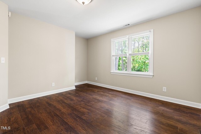 empty room with dark wood-style flooring and baseboards