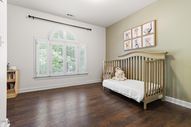bedroom with multiple windows, wood finished floors, and baseboards