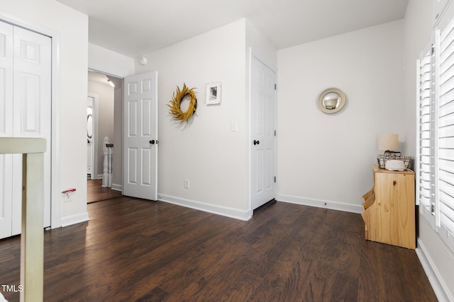 unfurnished bedroom with dark wood finished floors, baseboards, and arched walkways