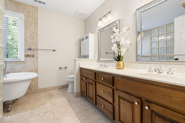 bathroom featuring a freestanding tub, tile patterned floors, double vanity, and toilet