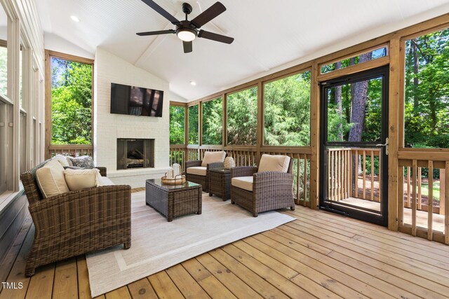 sunroom featuring a ceiling fan, lofted ceiling, and an outdoor living space with a fireplace