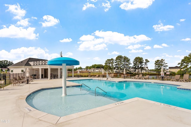 pool with a patio area and fence