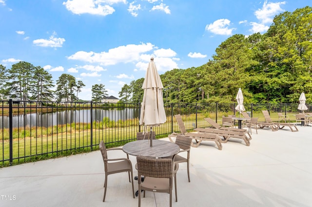view of patio / terrace featuring a water view, outdoor dining area, and fence
