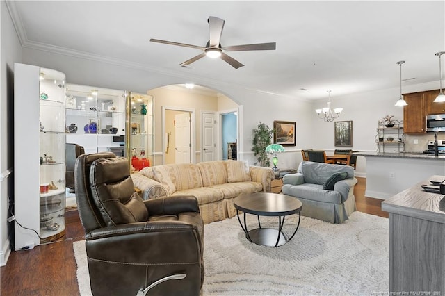 living room featuring ornamental molding, dark wood-style flooring, ceiling fan with notable chandelier, and arched walkways