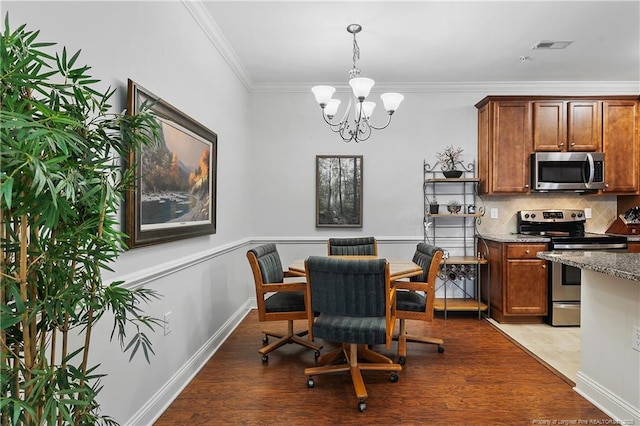 dining space featuring visible vents, wood finished floors, ornamental molding, and a notable chandelier