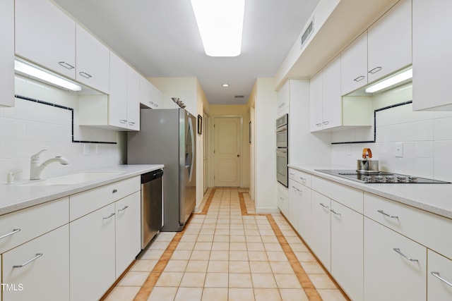 kitchen featuring a sink, stainless steel appliances, backsplash, and white cabinetry