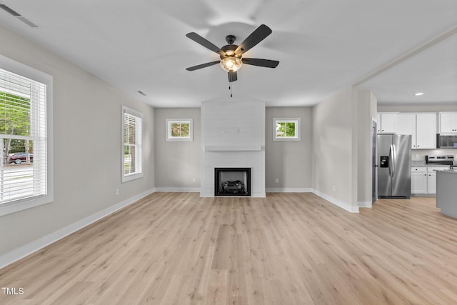 412 W Stallings St, Clayton, NC 27520 - unfurnished living room featuring baseboards, light wood-style floors, a large fireplace, and a ceiling fan