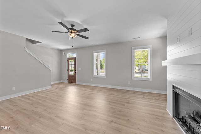 412 W Stallings St, Clayton, NC 27520 - unfurnished living room featuring light wood-type flooring, a healthy amount of sunlight, ceiling fan, and a large fireplace