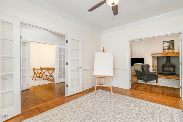 101 Rainbow Dr, Carrboro, NC 27510 - living area featuring french doors, crown molding, a wood stove, ceiling fan, and wood finished floors