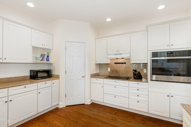 101 Rainbow Dr, Carrboro, NC 27510 - kitchen featuring black appliances, under cabinet range hood, dark wood finished floors, white cabinetry, and backsplash