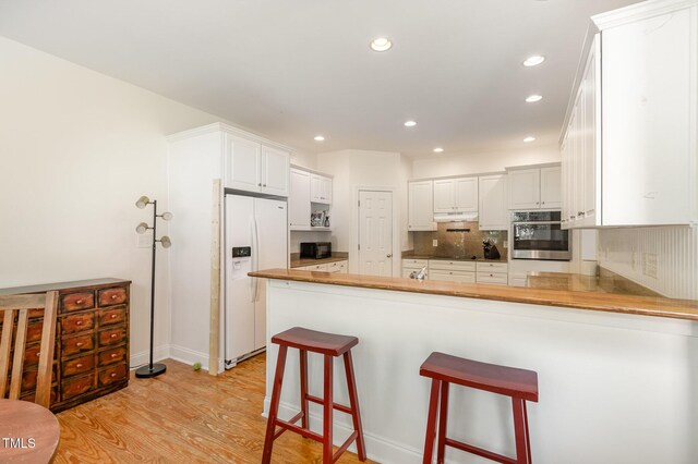 101 Rainbow Dr, Carrboro, NC 27510 - kitchen featuring black appliances, a peninsula, light wood-style floors, under cabinet range hood, and backsplash