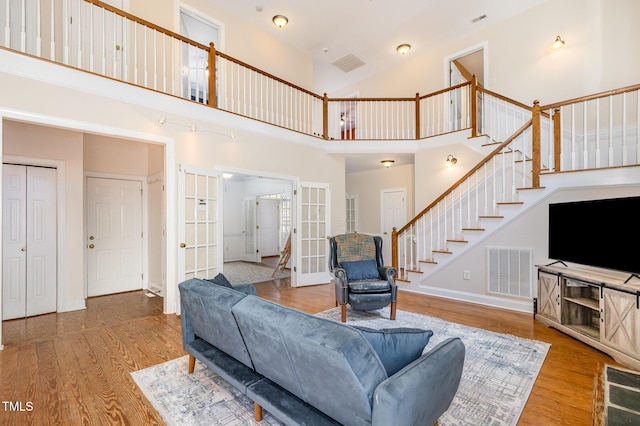 101 Rainbow Dr, Carrboro, NC 27510 - living room with french doors, a towering ceiling, stairway, wood finished floors, and baseboards