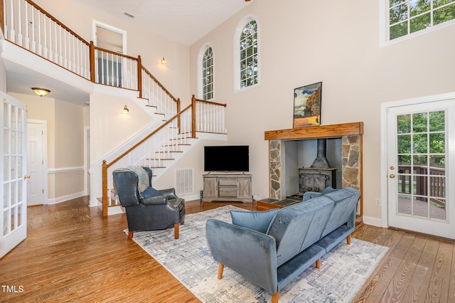 101 Rainbow Dr, Carrboro, NC 27510 - living area featuring a towering ceiling, healthy amount of natural light, wood finished floors, stairs, and a wood stove