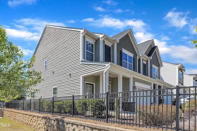 view of side of home featuring a fenced front yard and an attached garage
