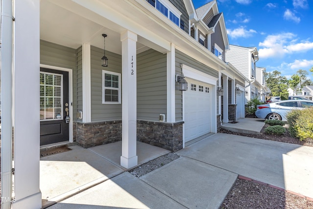 property entrance featuring a garage, stone siding, a porch, and concrete driveway